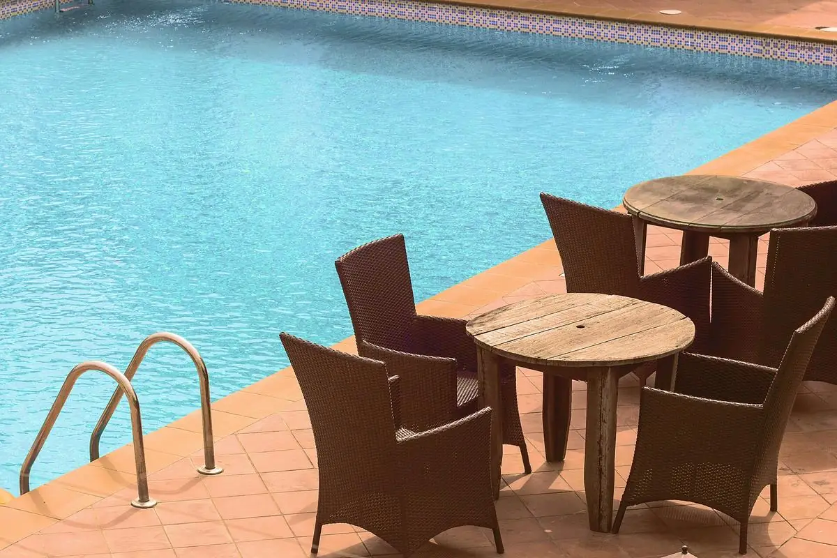Piscina azul com área de lazer e cadeiras na borda